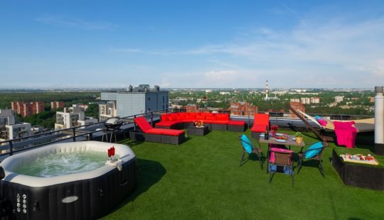 Relax zone on rooftop terrace. Table, cozy furniture and outdoor jakuzzi. Sunny summer day.