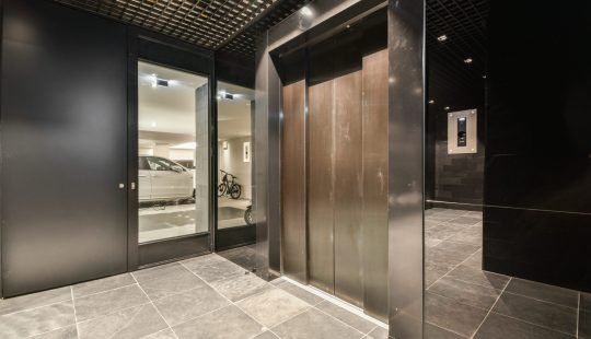 the inside of a building with two doors and one door opened to reveal a car parked in the parking lot