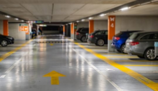 Yellow markings with blurred modern cars parked inside closed underground parking lot.
